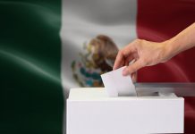 Urnas y boletas electorales con mapa de Yucatán de fondo.