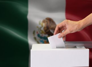 Urnas y boletas electorales con mapa de Yucatán de fondo.